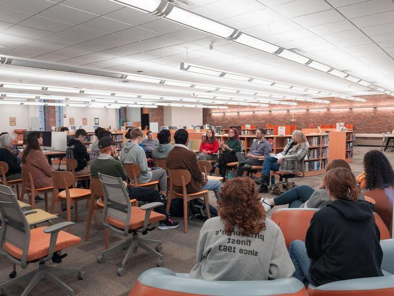 Students and guests listen to faculty speaking panel in library